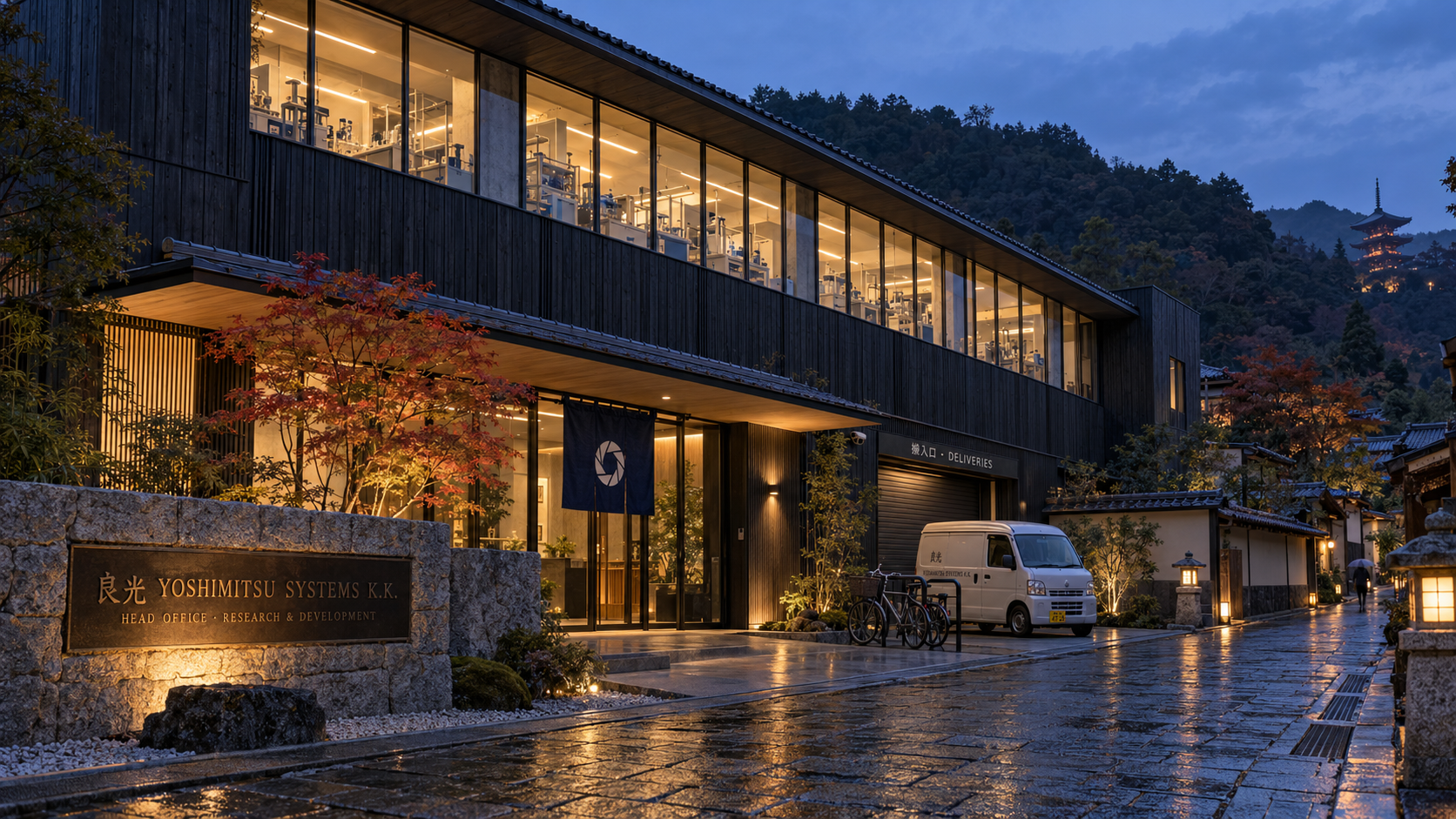 Yoshimitsu Systems head office in Kyoto at rainy dusk: a low charred-timber building with amber-lit labs behind a long upper window, a granite wall with a bronze 良光 plaque, an indigo noren with the aperture emblem at the entrance, a red maple, and a pagoda on the forested hill behind